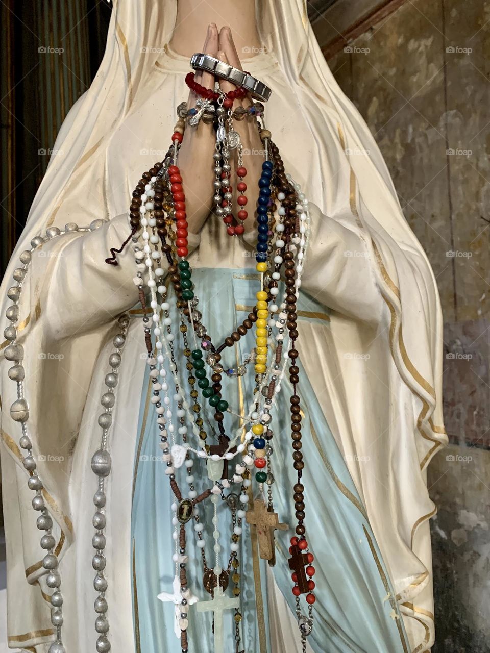 A statue depicting the Madonna who is entrusted with prayers and vows through the rosaries that are hung on her hands.