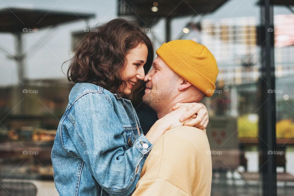 Happy stylish young family couple in love hipsters having fun against glass wall