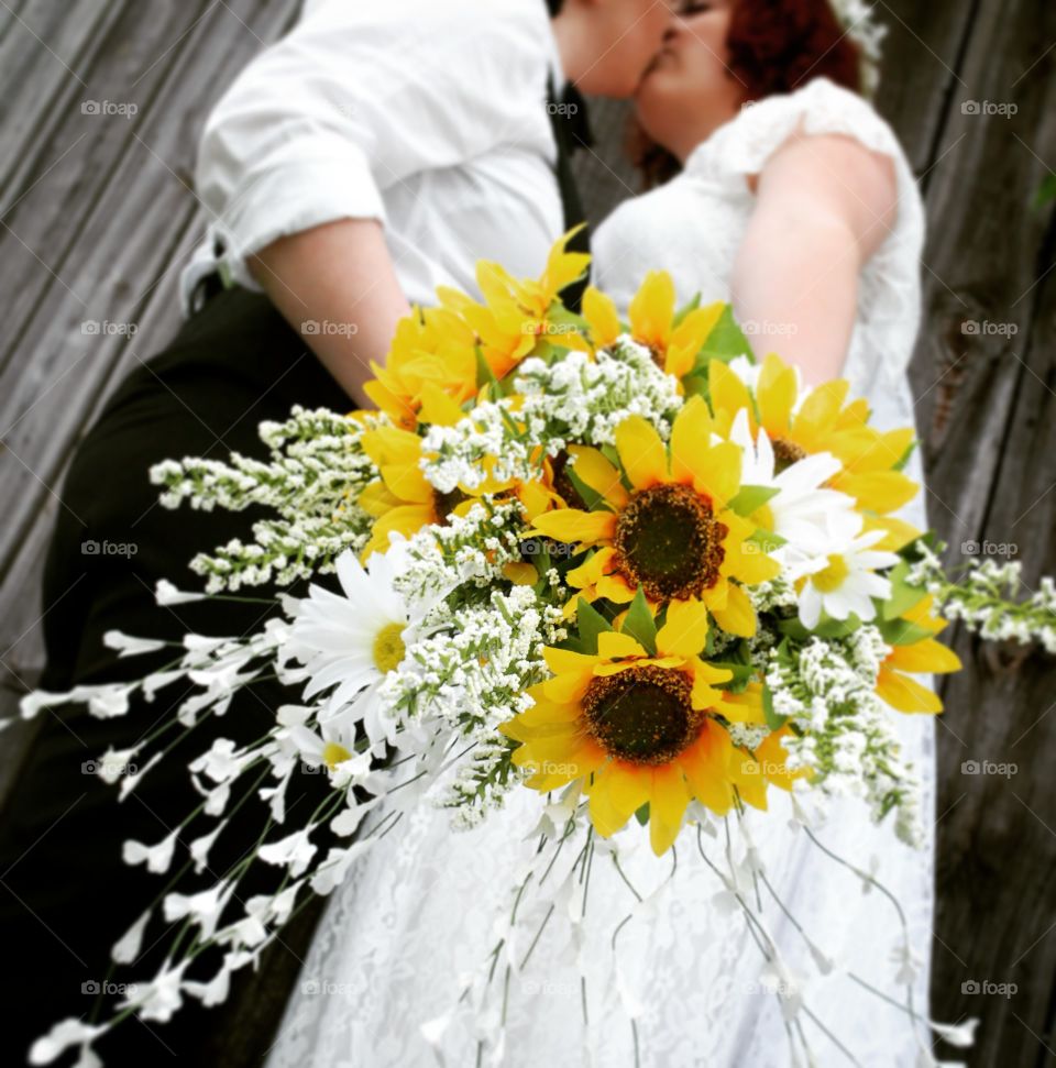 Married women holding sunflower bouquet and kissing