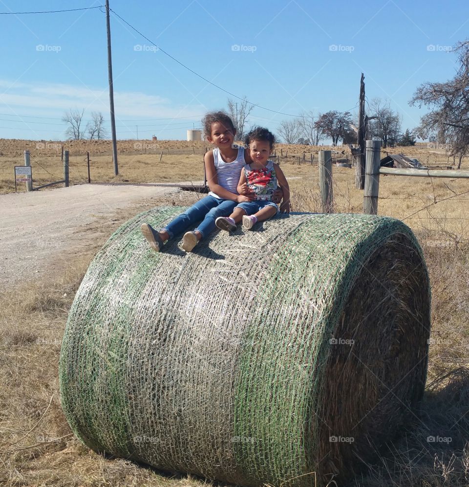 Happy siblings sitting on hay