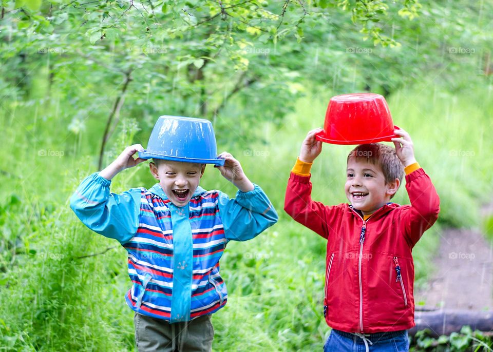 Children Playing in Rainy Spring Day with Buckets on Their Heads