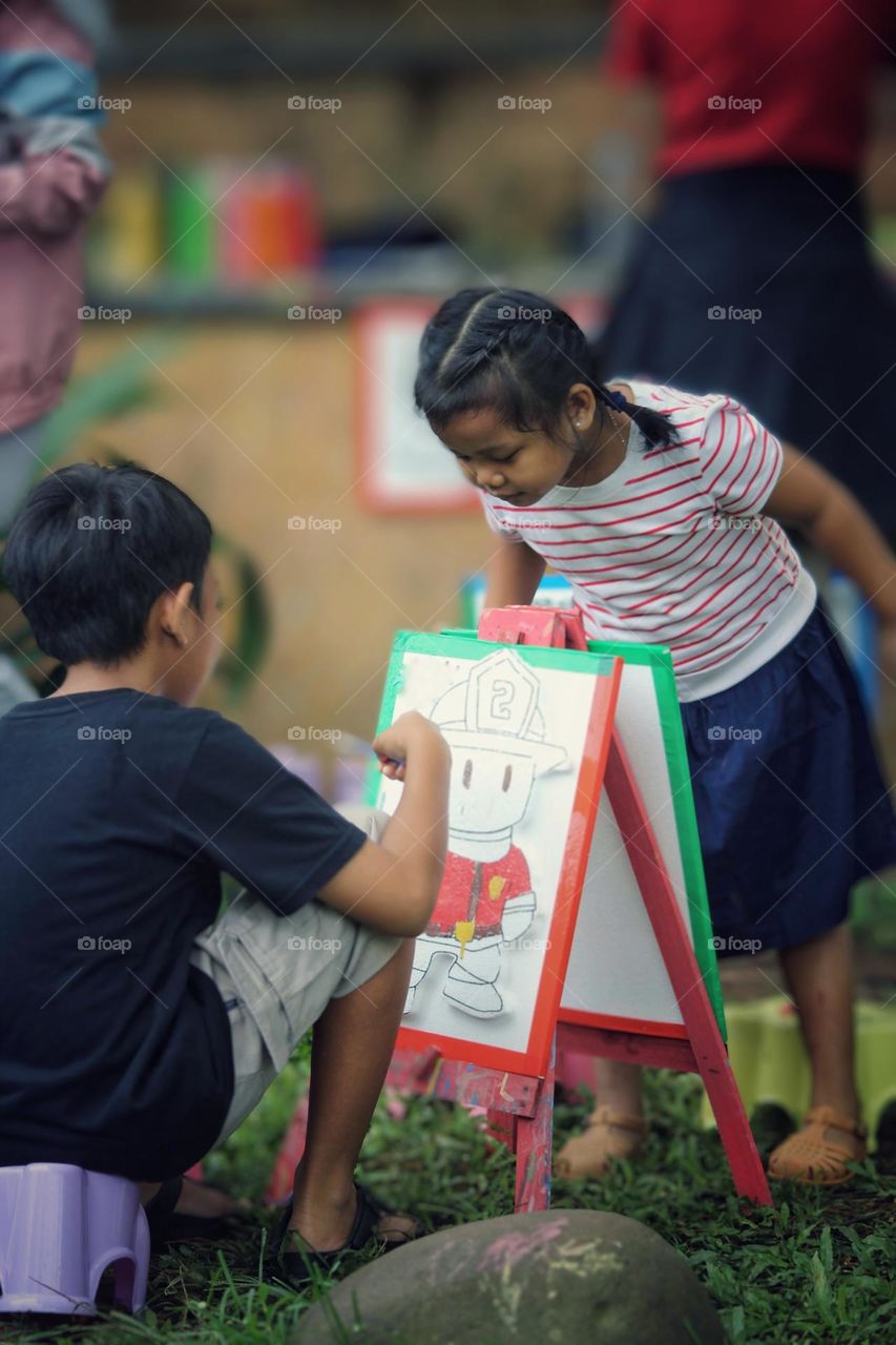 Two small children are coloring a picture.