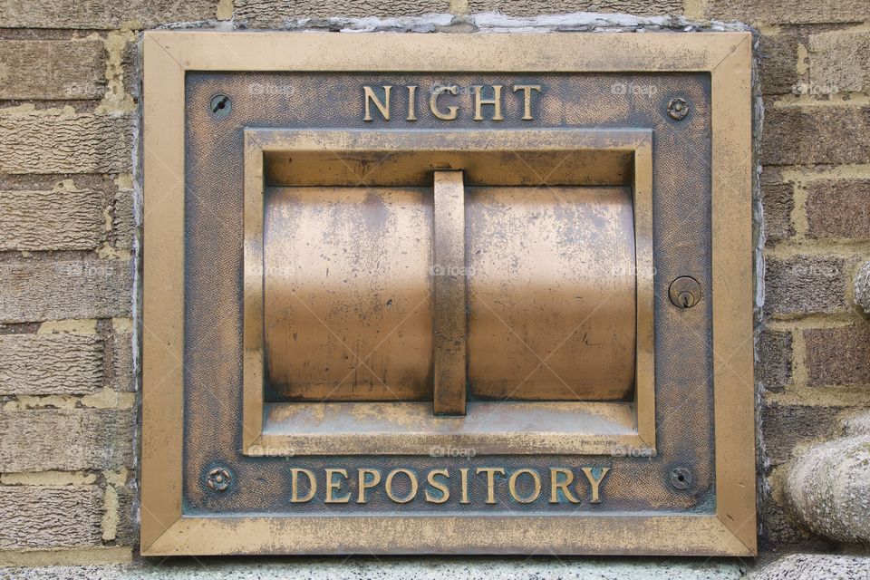A retro outside night bank depository box for commercial customers on a brick wall.