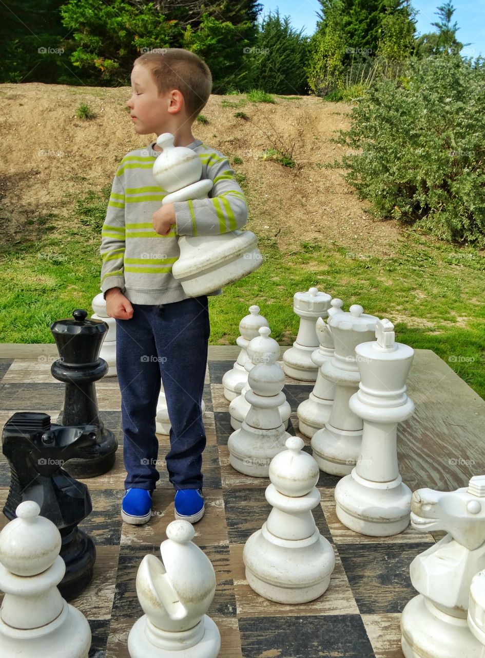 Boy Standing On Giant Chessboard 