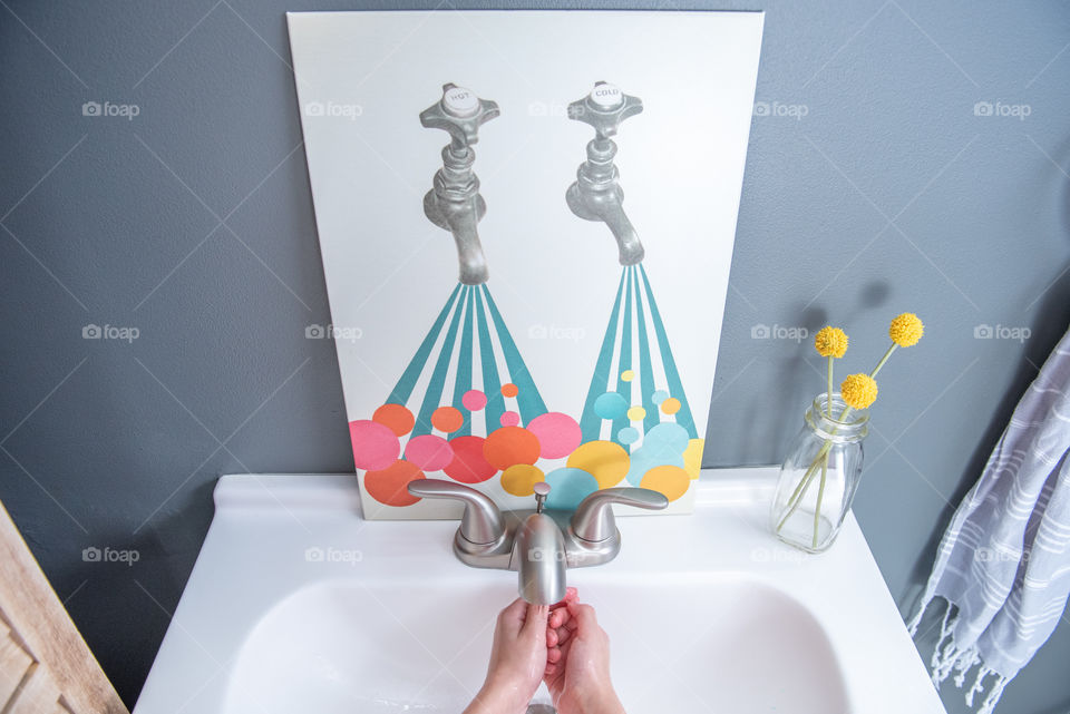 Picture of a pair of vintage faucets on a bathroom vanity sink with someone washing their hands