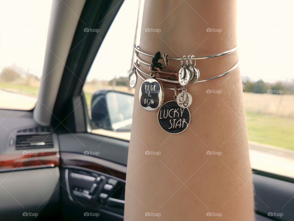 A woman's arm with bangle bracelets riding in a car from A to B