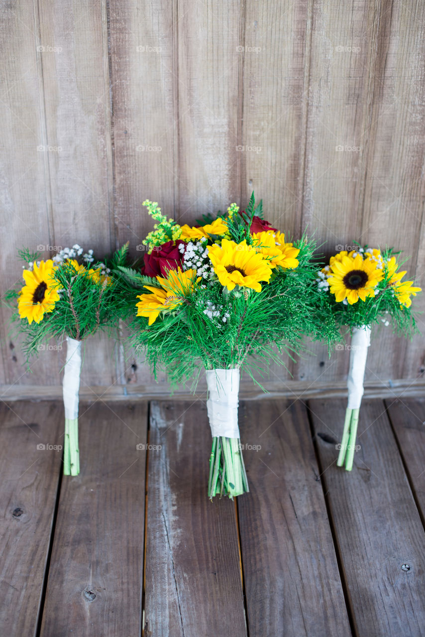 Three sunflower bridal bouquets on wood porch lined up