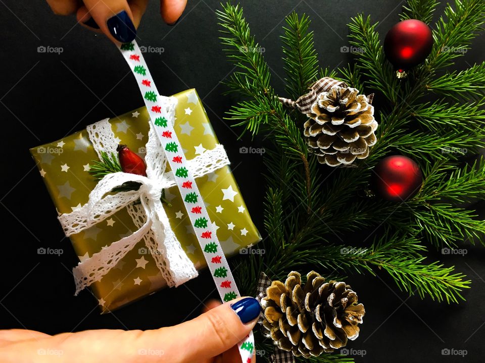 Woman's hand holding ribbon against christmas gift