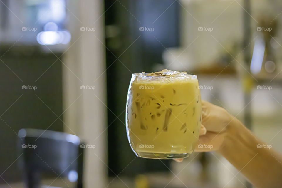 Hand holding Iced coffee in a glass.