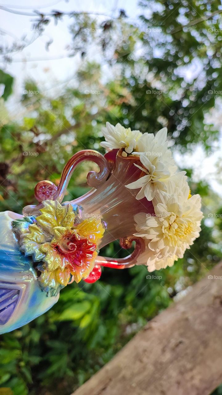 Beautiful white flowers in a colourful flowerpot with a flower sculpture, Flowers in a vase, colourful vase, white flowers in a vase