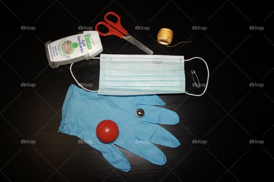 In the photograph there is a protective mask for the virus, a pair of scissors, a clip, a small bell, disinfectant gel and a glove. I have taken the photograph closely so that the objects can be seen well.