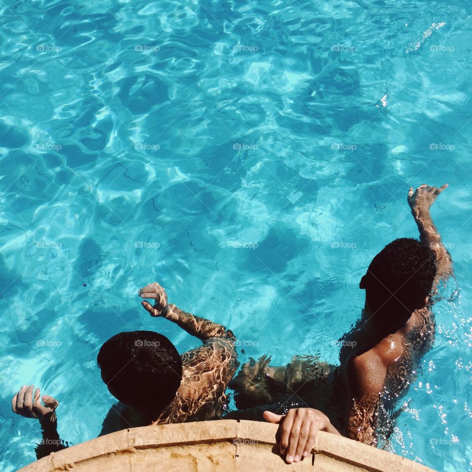 Two men in swimming pool with sun rays