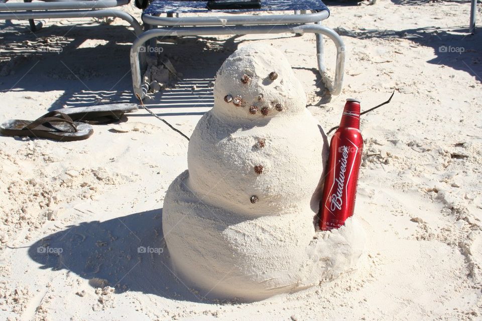 Sand snowman enjoying a beer