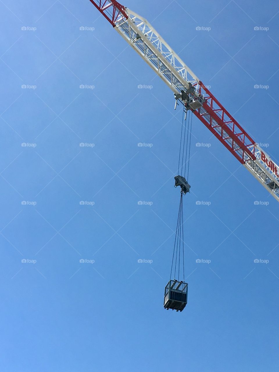 Building construction crane high up on building against blue sky