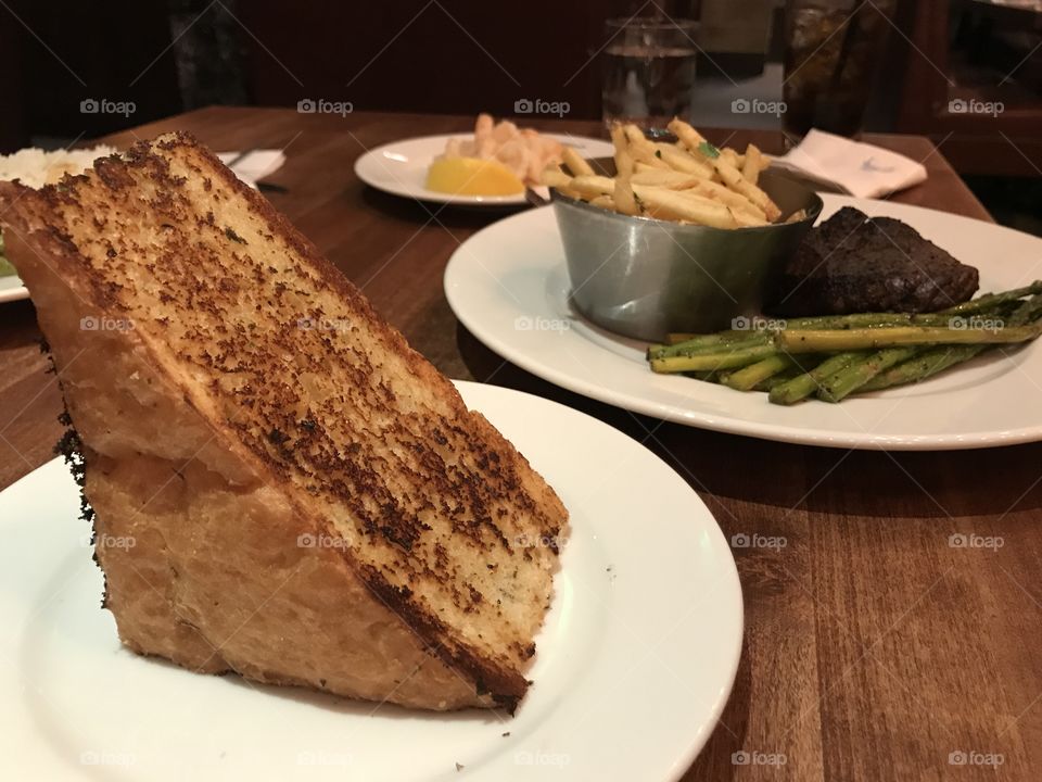 Food, garlic bread, looks like cheese block, fries, steak. 