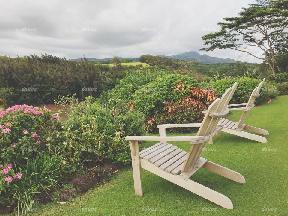 Lawn chairs in yard overlooking a view. 