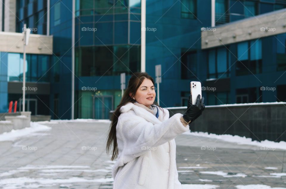 Portrait of young happy business woman relaxing,  working in winter city. Laptop. Phone. Technology. Selfie.  Social media.  Video call