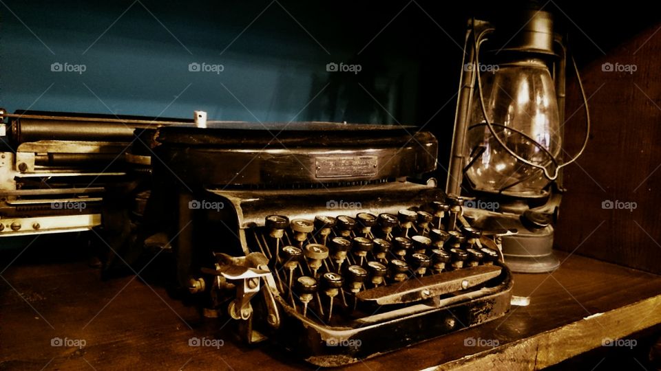 Typewriter with oil lamp on wooden desk