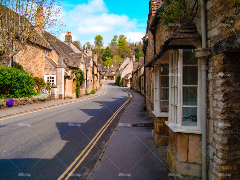Quaint English historic village in countryside with stone houses and single lane road