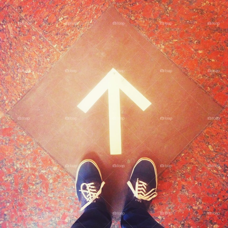 Blue shoes in front of the white arrow on the floor