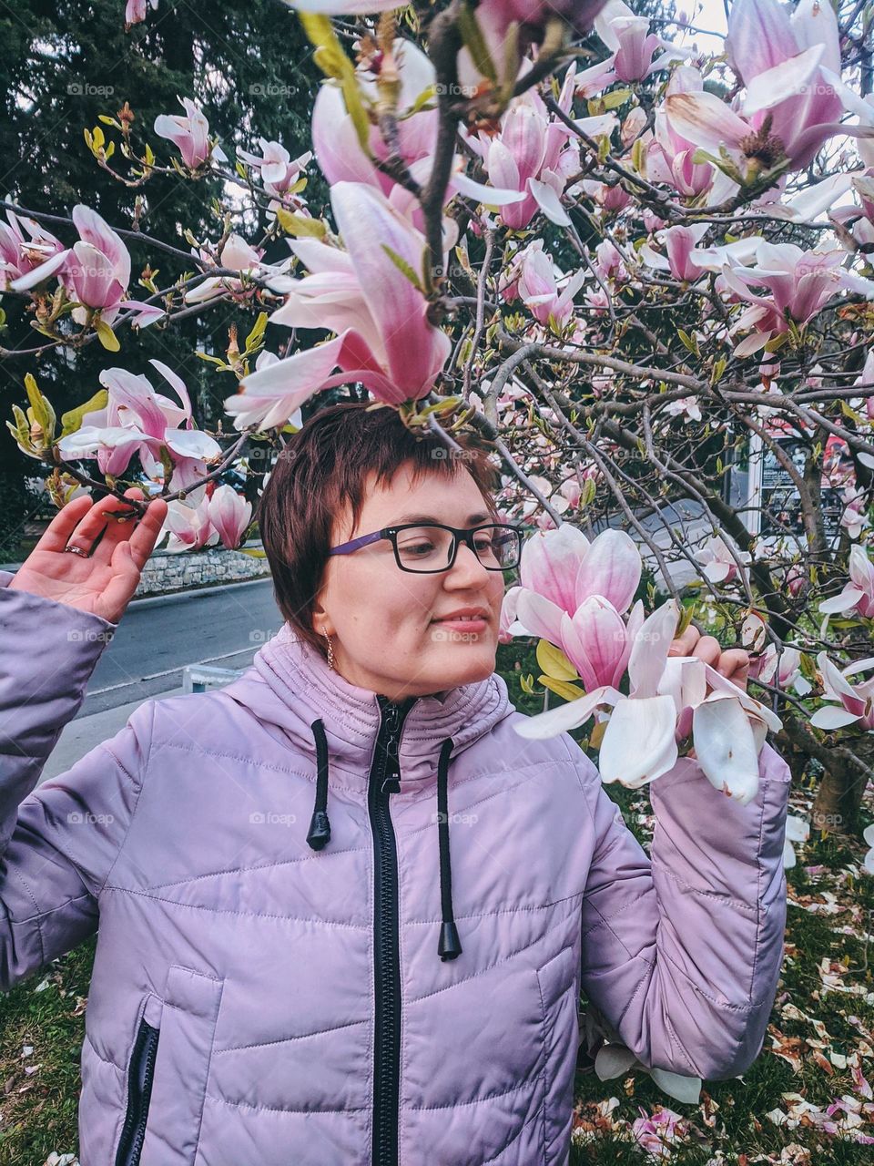 Portrait of beautiful young redhead woman in magnolia park in spring