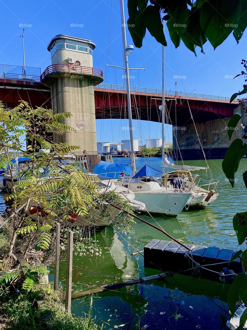 This is beautiful “Newtown Creek” by the “Pulaski Bridge” in LIC, Queens on a warm sunny Indian summer day in early October 2023. Sailboats are visible through the foliage of the bushes on the narrow strip of land. Hypnotic Productions