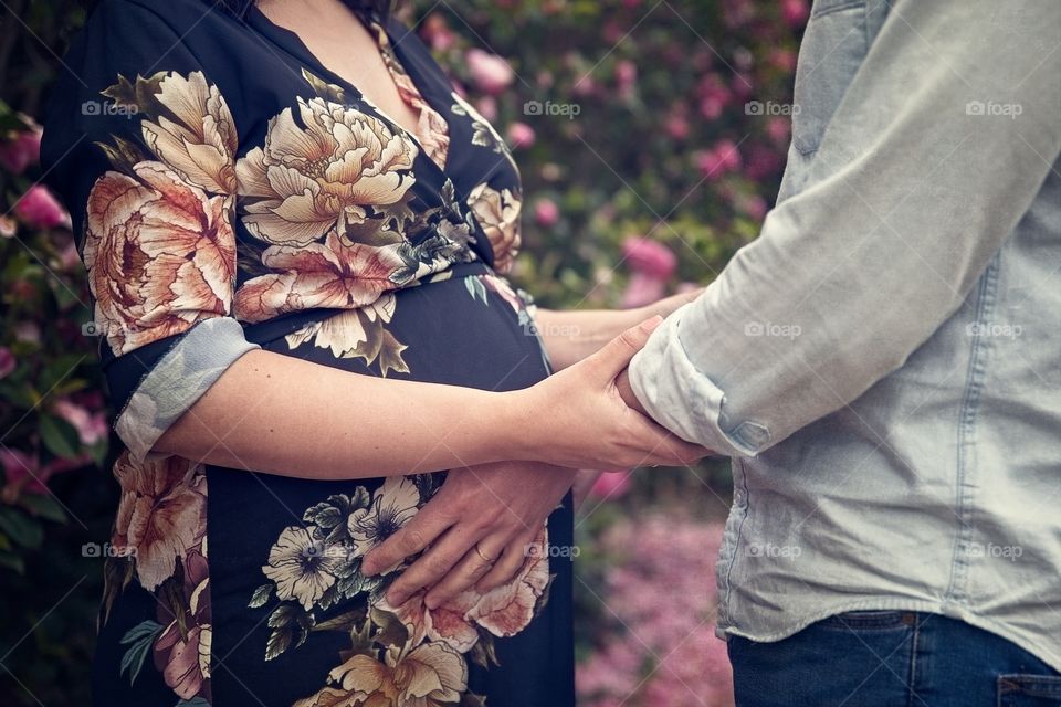 Pregnant couple holding hands on her belly