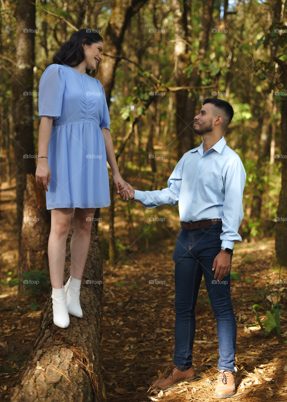 Couples of young people sitting in middle of the forest while looking into their eyes each other, in a sunny day.