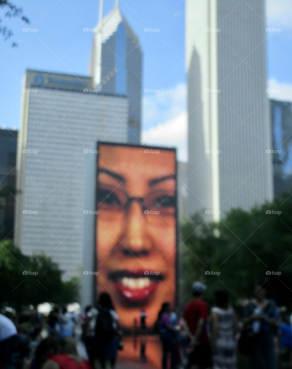 Wall with a huge portrayal of a human face on the side. City skyline in the background