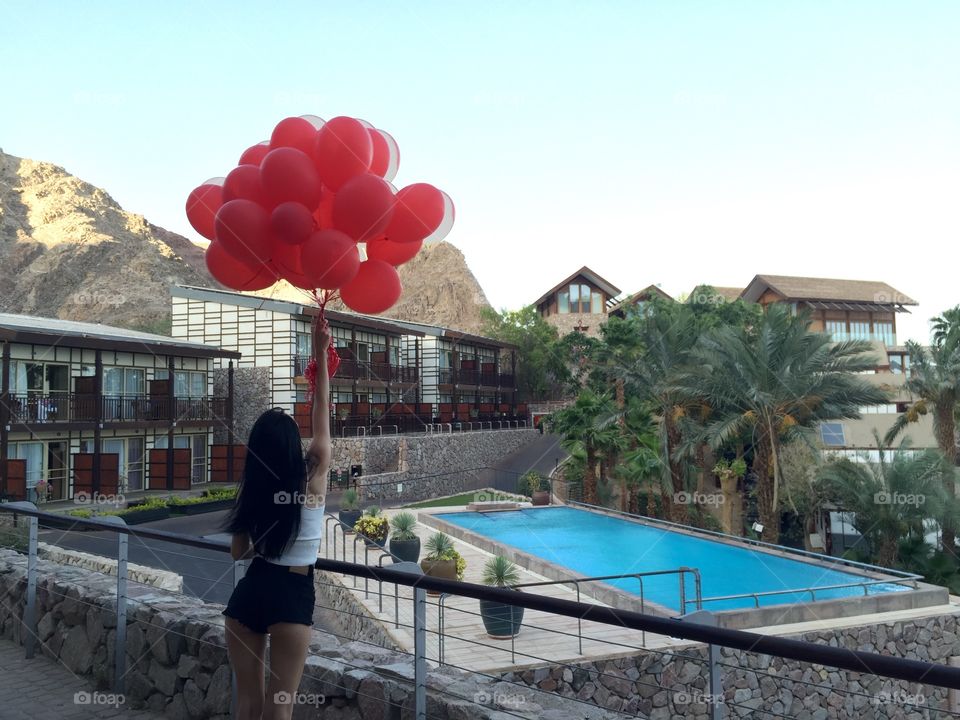 Woman standing in front of resort holding balloons in hand