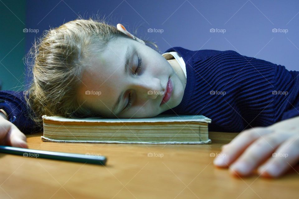 the girl was tired from homework and fell asleep on a book