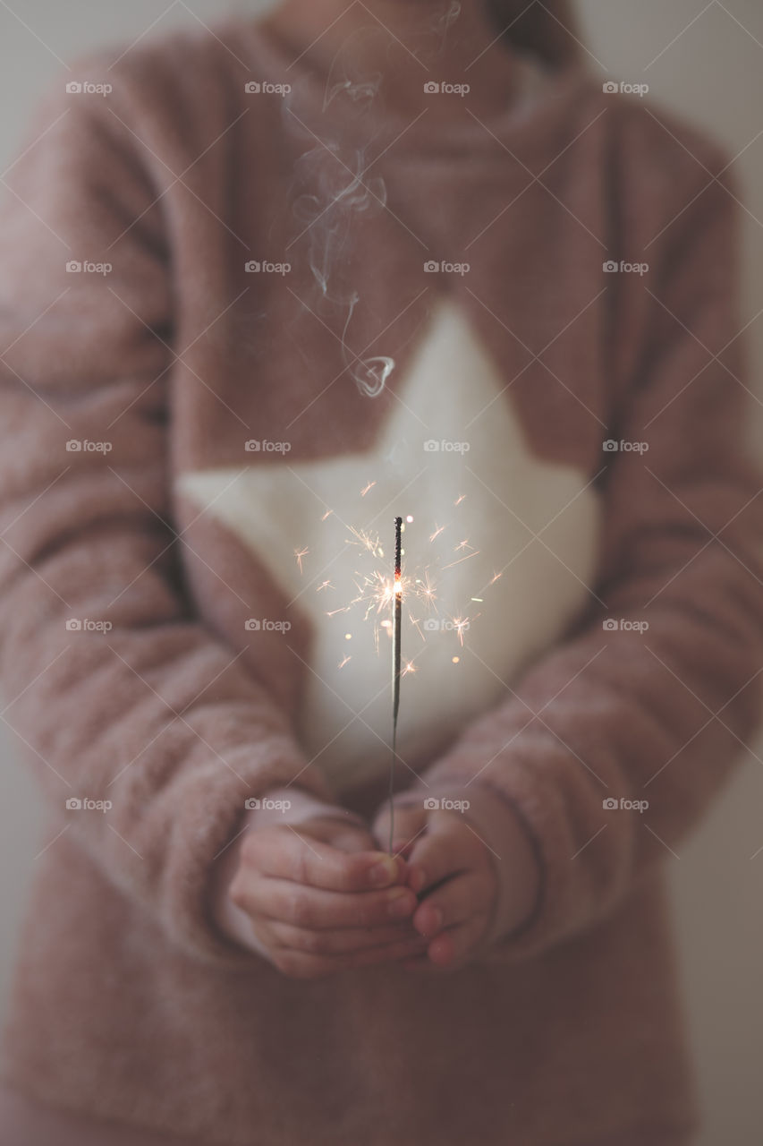 Closeup of young girl wearing warm sweater and holding sparkler