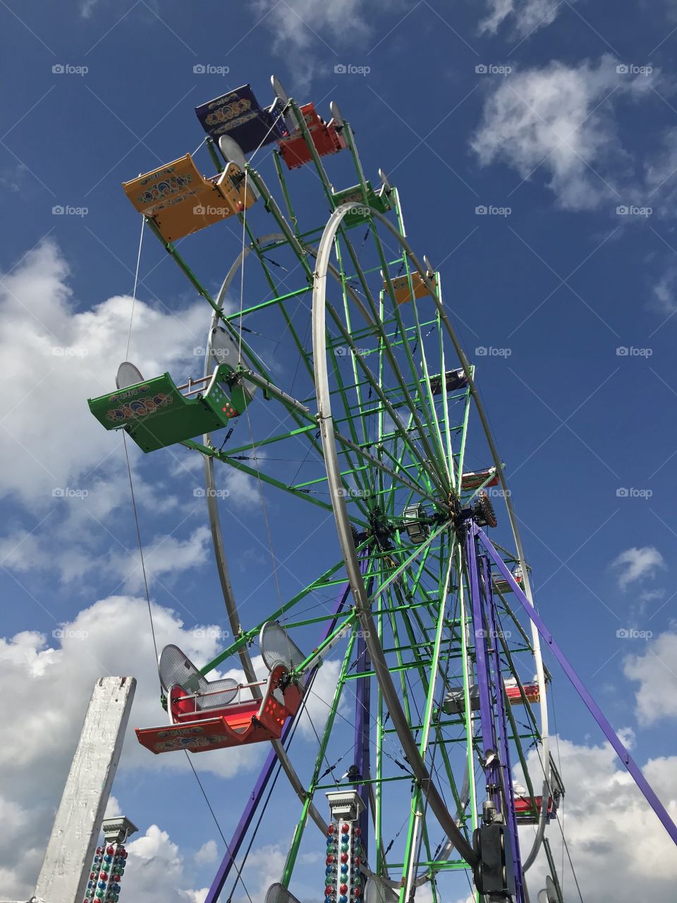 Ferris wheel at a carnival with blue sky and white clouds