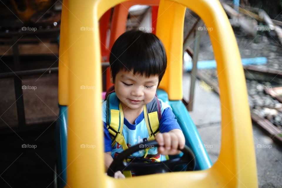 Asian child in toy car