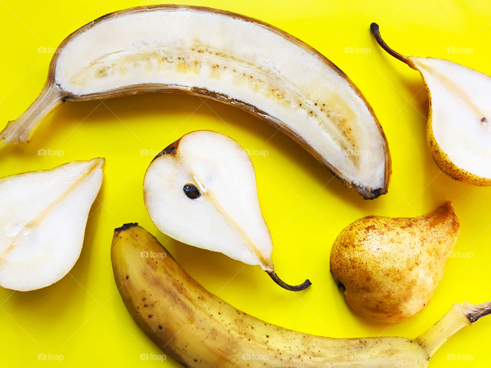 Ripe slices of yellow Bananas and yellow pears on yellow background 