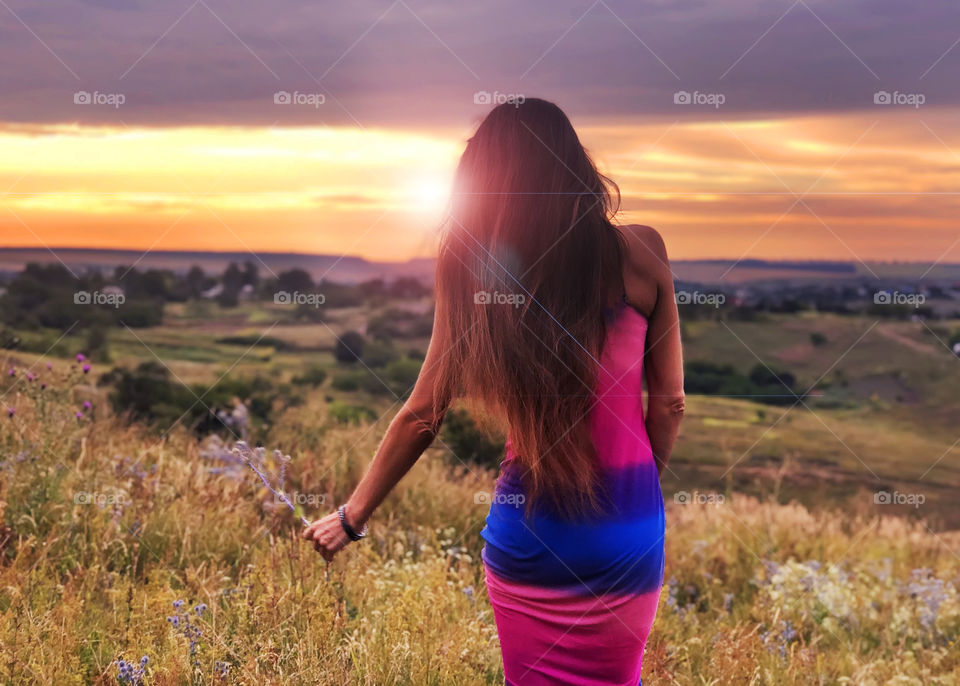 Young woman with long hair in the field at sunset 