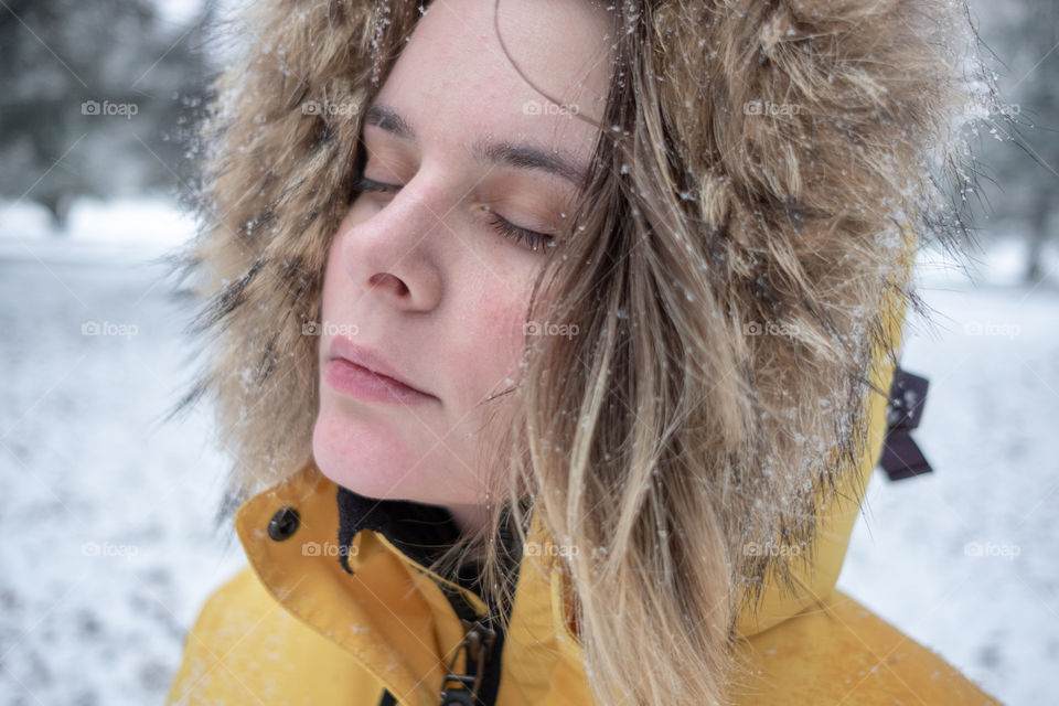 Young woman portrait with closed eyes under falling snow