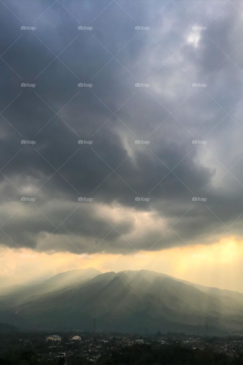 The towering mountains are illuminated by sunlight. Mountain. Hill. Light. Ray. Sun. Sunlight. Photography. Scenes. Scenery. Tranquil scene. Tranquil. Landscapes. Mountains. Afternoon sky. Dusk. Cloud