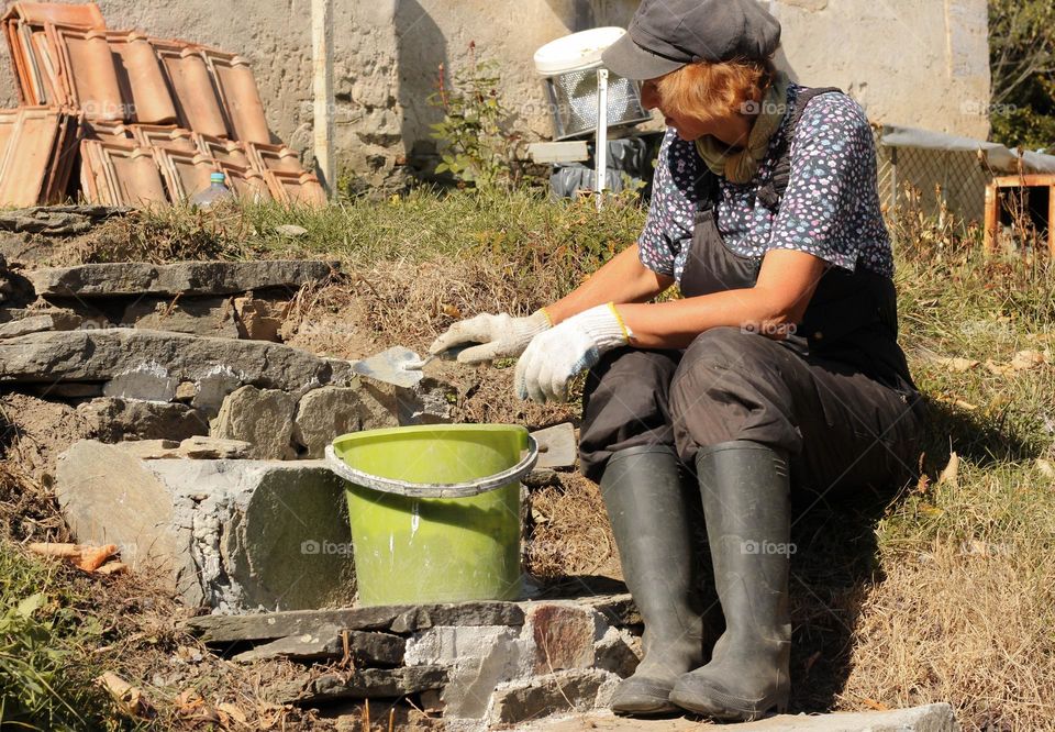 A woman makes plaster with concrete outdoor