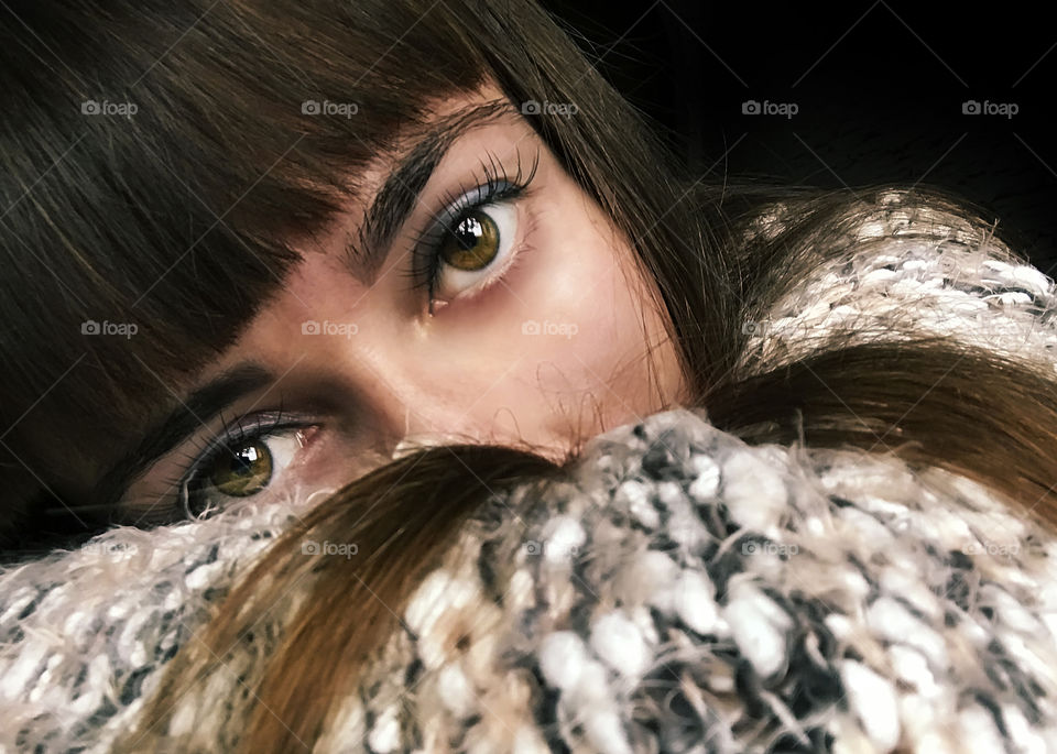 Portrait of a young woman with hazel eyes and chestnut hair wearing a cozy knitted sweater 