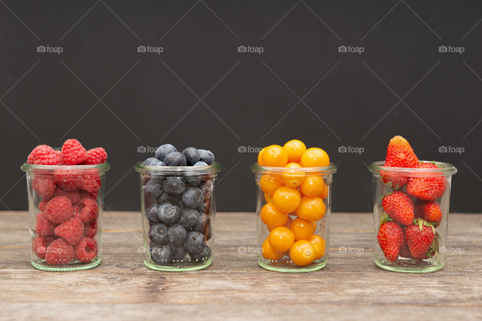four glasses of berries in a row