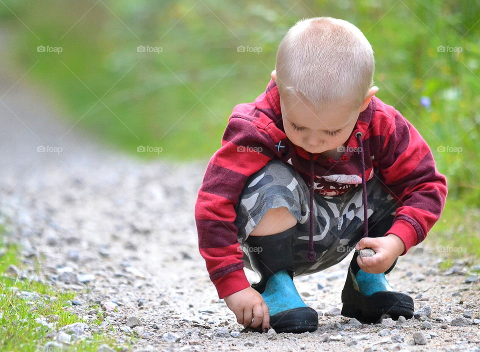 Boy looking at rocks in the road