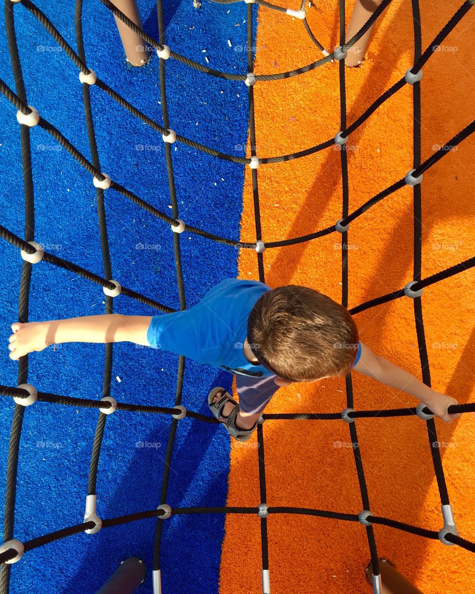 Little boy climbing on ropes