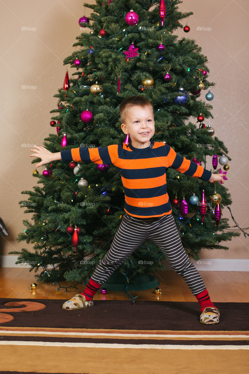 Happy toddler boy in front of Christmas tree