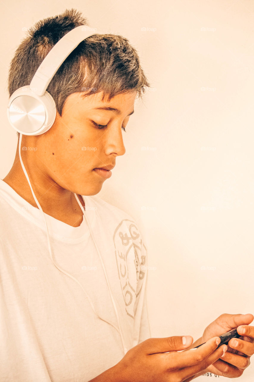 Young handsome man in white with headphones and smartphone