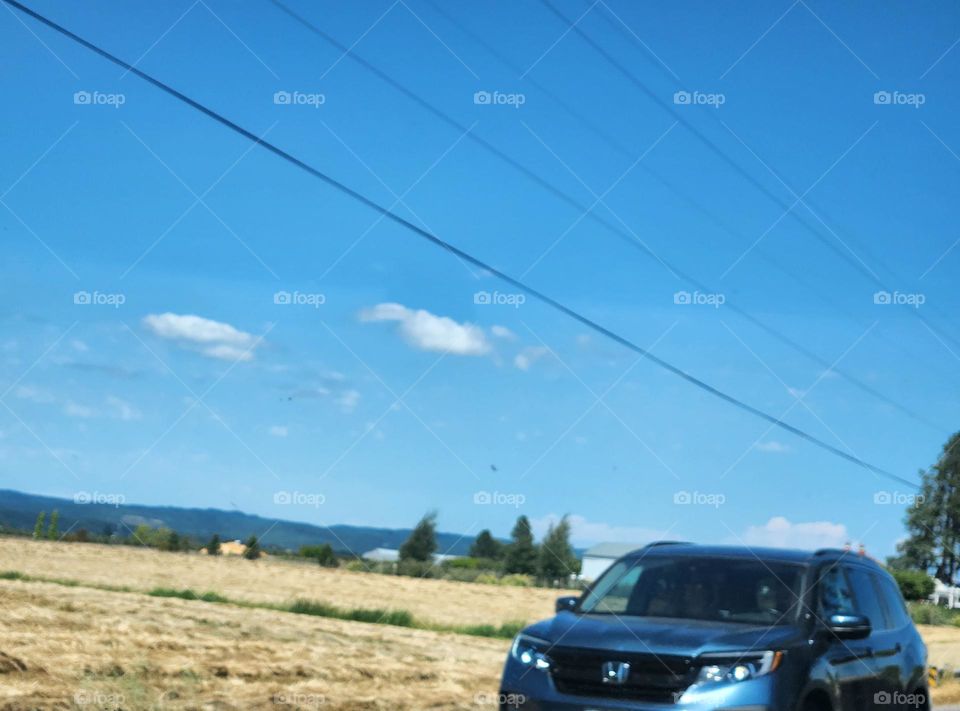 blue car and bright blue sky on a Summer road trip through Oregon countryside