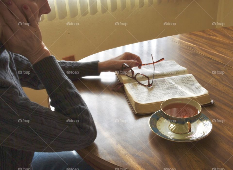 Woman reading the Bible, cup of tea on a saucer 