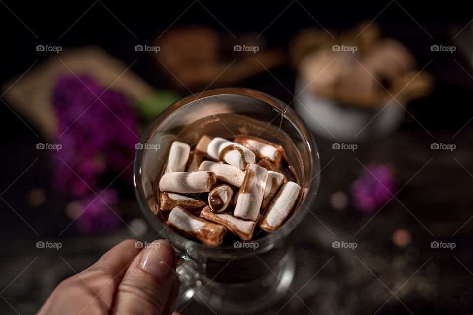 Hands holding coffee cup with marshmallows
