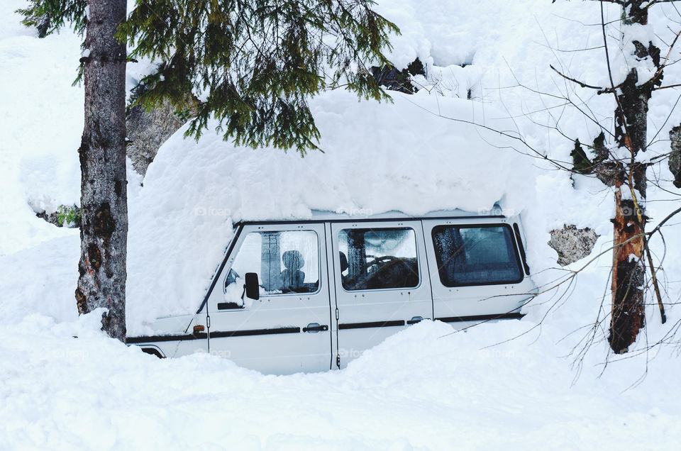 Scenic view of winter landscape in the forest. A frozen car under a pile of white snow.