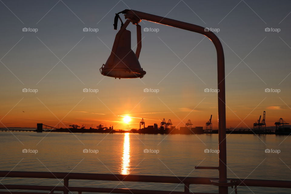 The lamppost on the dock of the boat aligned with the sunset light reflecting in the ocean .. what a nice view from the ferry ride!